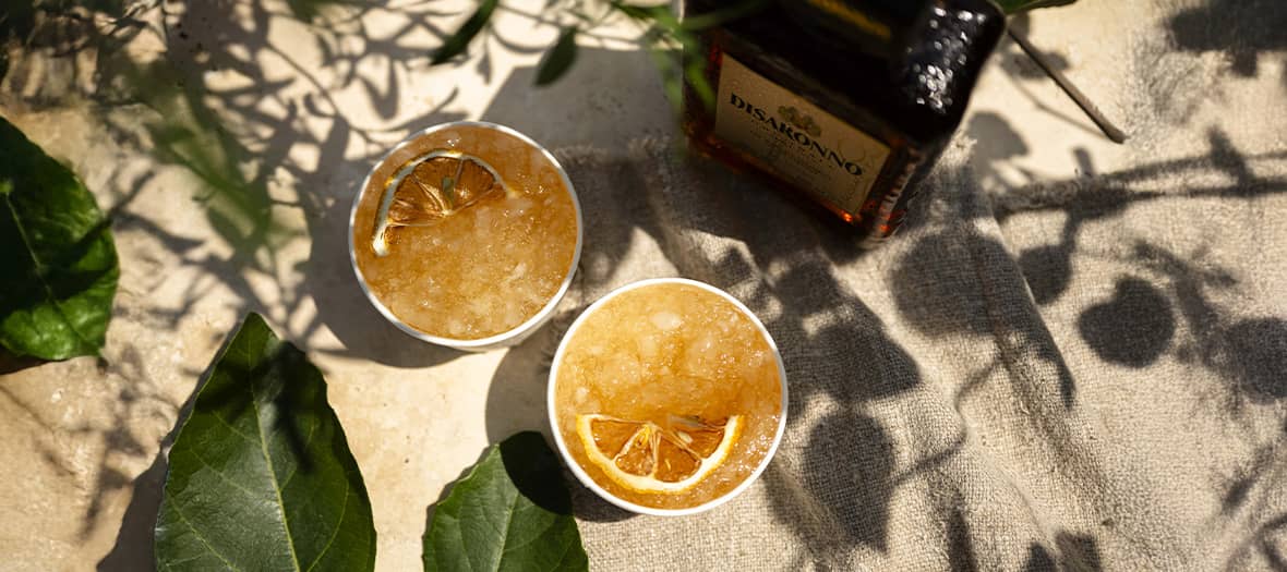 Deux verres de cocktail rafraîchissant au Disaronno avec glaçons pilés et tranche de citron séché, recette d’apéritif estival à base d’amaretto.